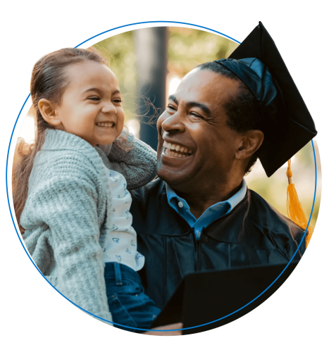 Graduating dad wearing a cap and gown smiles while holding daughter Graduating dad wearing a cap and gown smiles while holding daughter