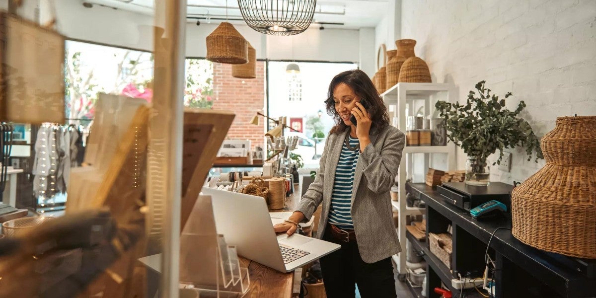 Woman talking on the phone while working on her laptop.