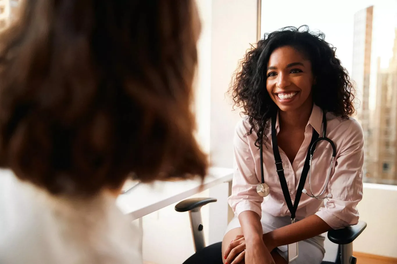 Woman having consultation with female doctor in hospital office.
