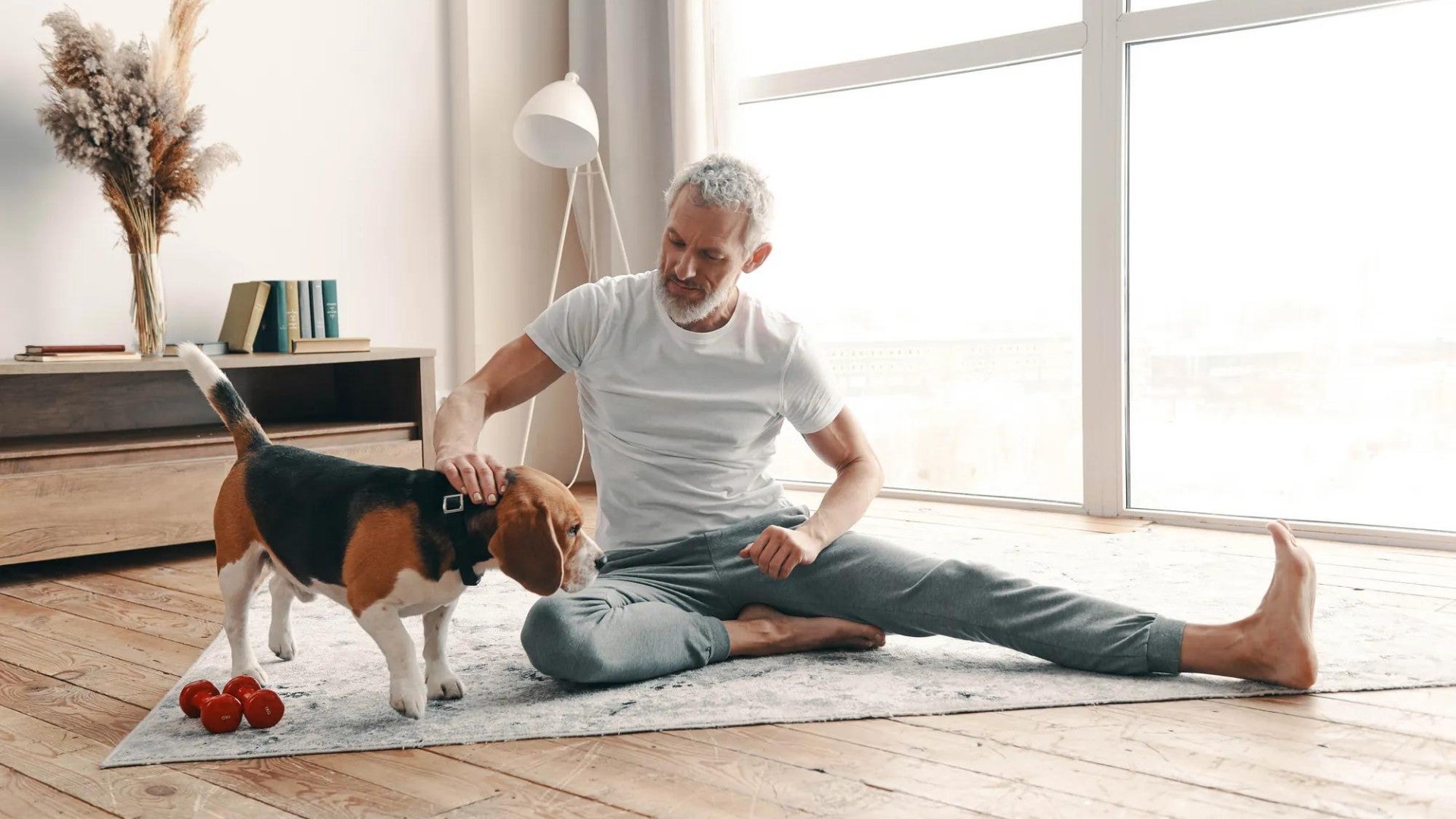 Man sitting on floor, stretching, while petting his dog. Man sitting on floor, stretching, while petting his dog.