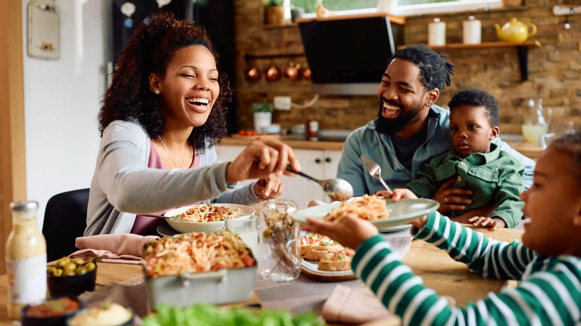 Familiy with parents and two children gathered around a table eating a meal. Familiy with parents and two children gathered around a table eating a meal.