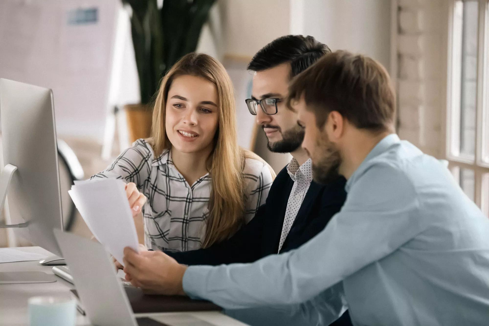 Colleagues discuss company financial paperwork together.