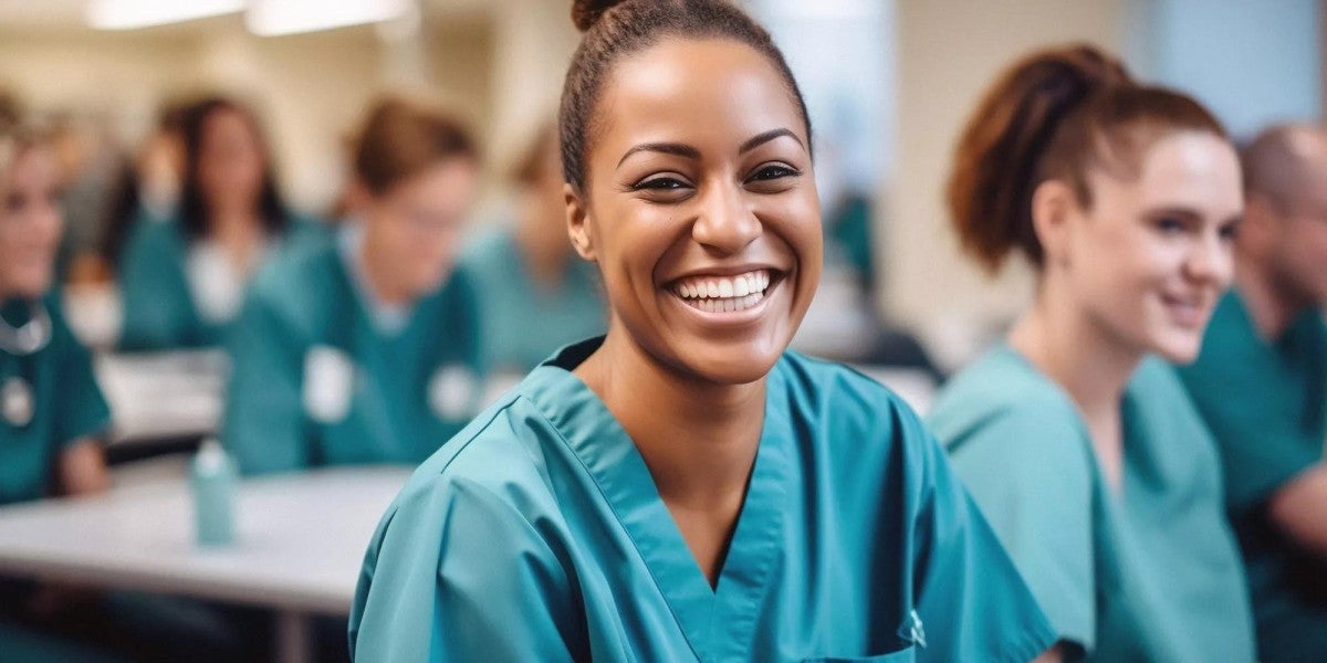  Image of a nurse smiling within a classroom of other nurses. 