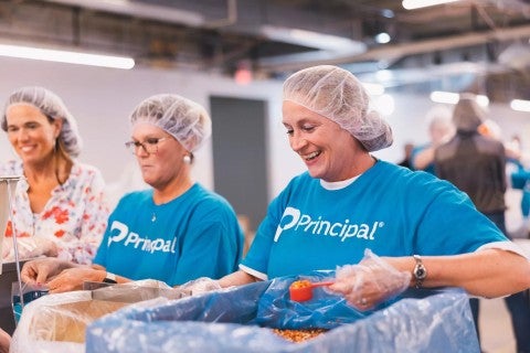Principal volunteers packing meals for Meals for the Heartland