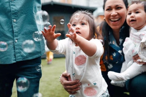 Woman with her two children, who are playing with bubbles
