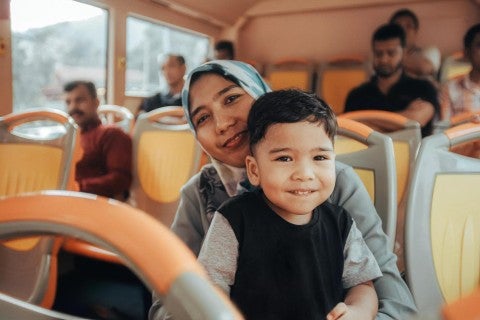 Mother and toddler son sitting on a bus together.
