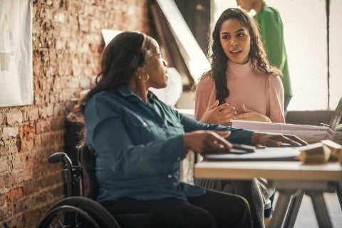 Two women sitting at a table discussing talent attraction and retention strategies.