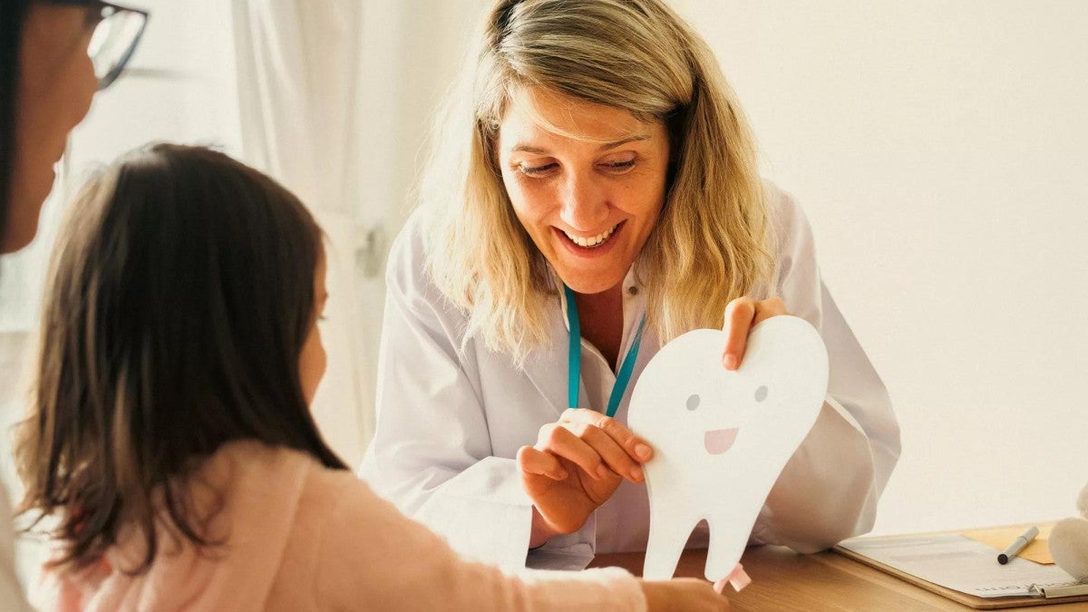 A dentist talking to a young patient and her mother.