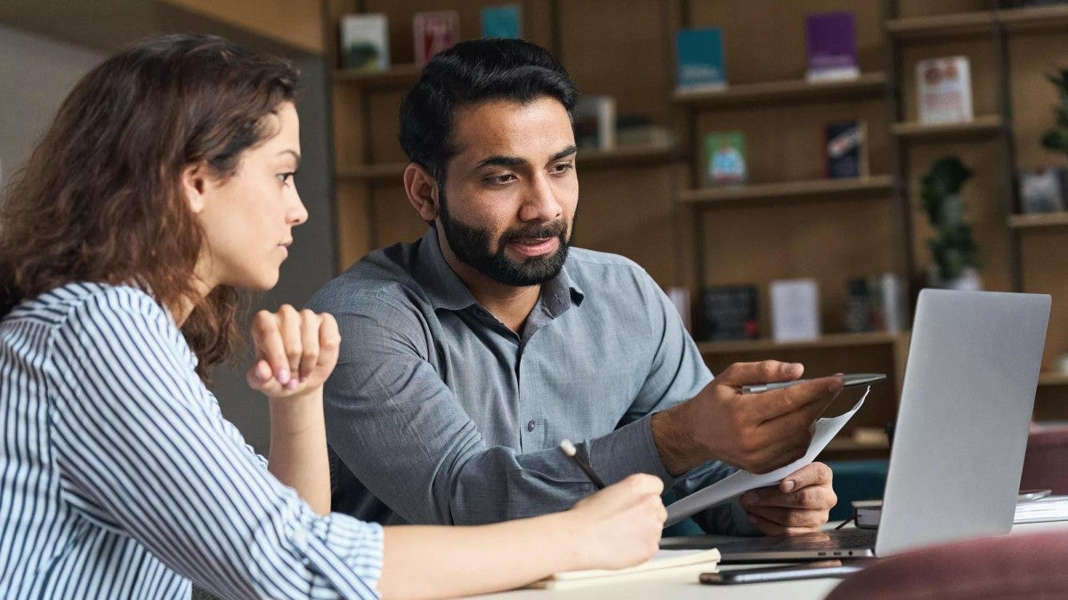 A man and woman look at a laptop in a small business setting.