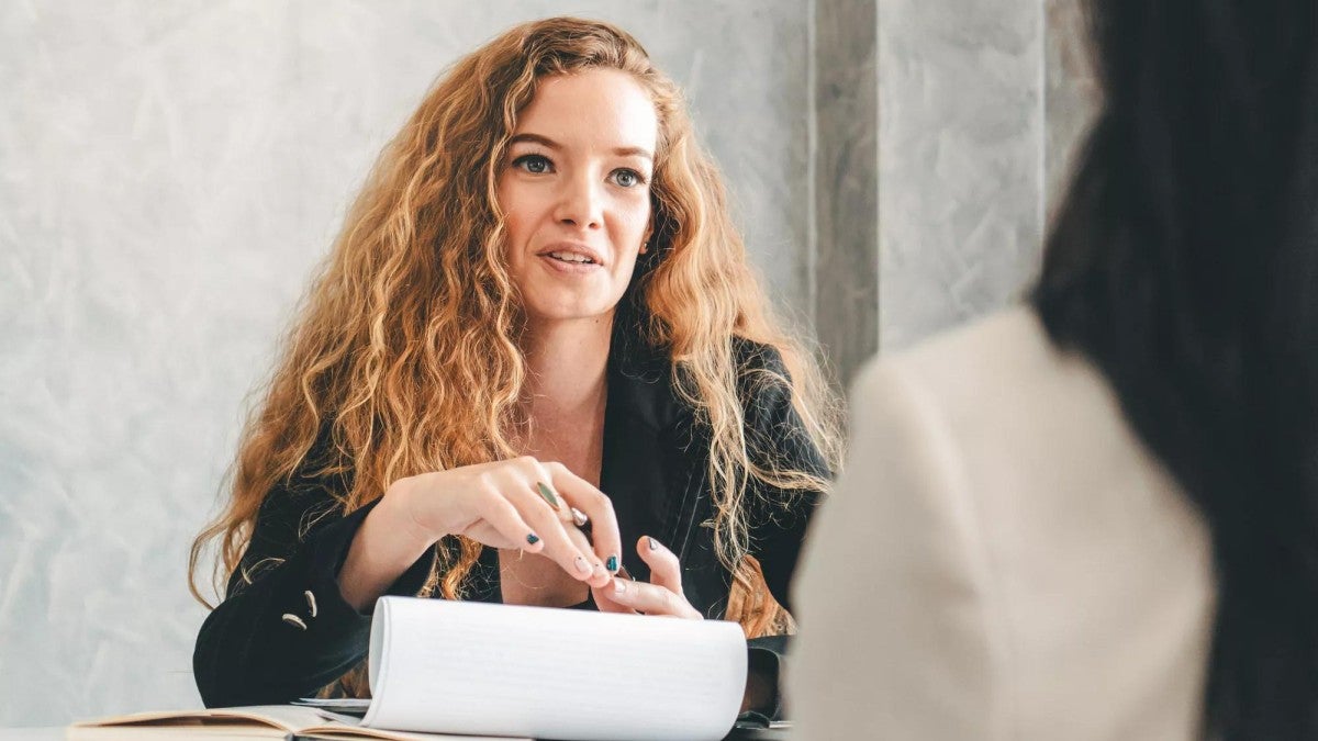 A woman speaking to a co-worker in an office setting.