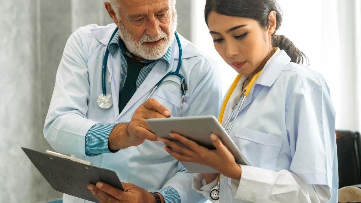 An experienced doctor going over a chart with a younger doctor.