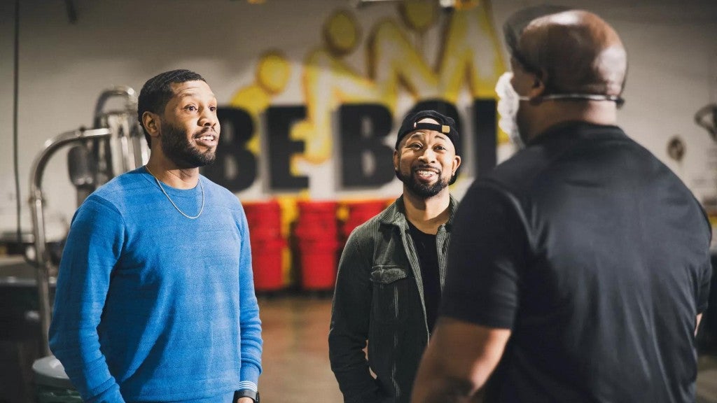 Business owners smiling while talking to their employee working in a roastery. 