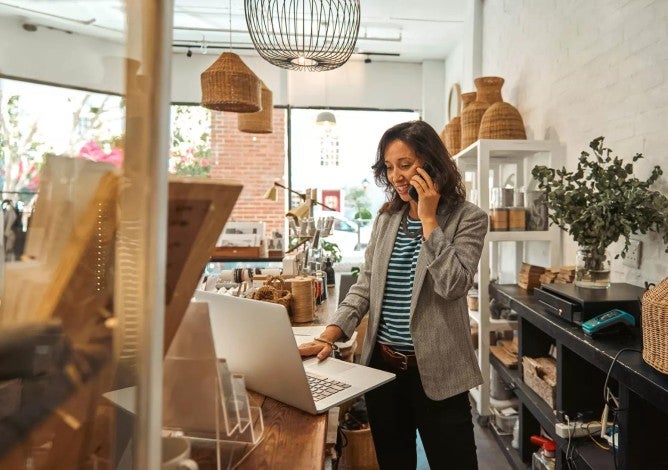 Woman business owner working on benefits plan on computer in her shop