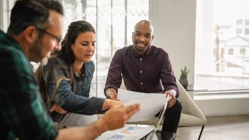 Three employees work together to review retirement solutions.