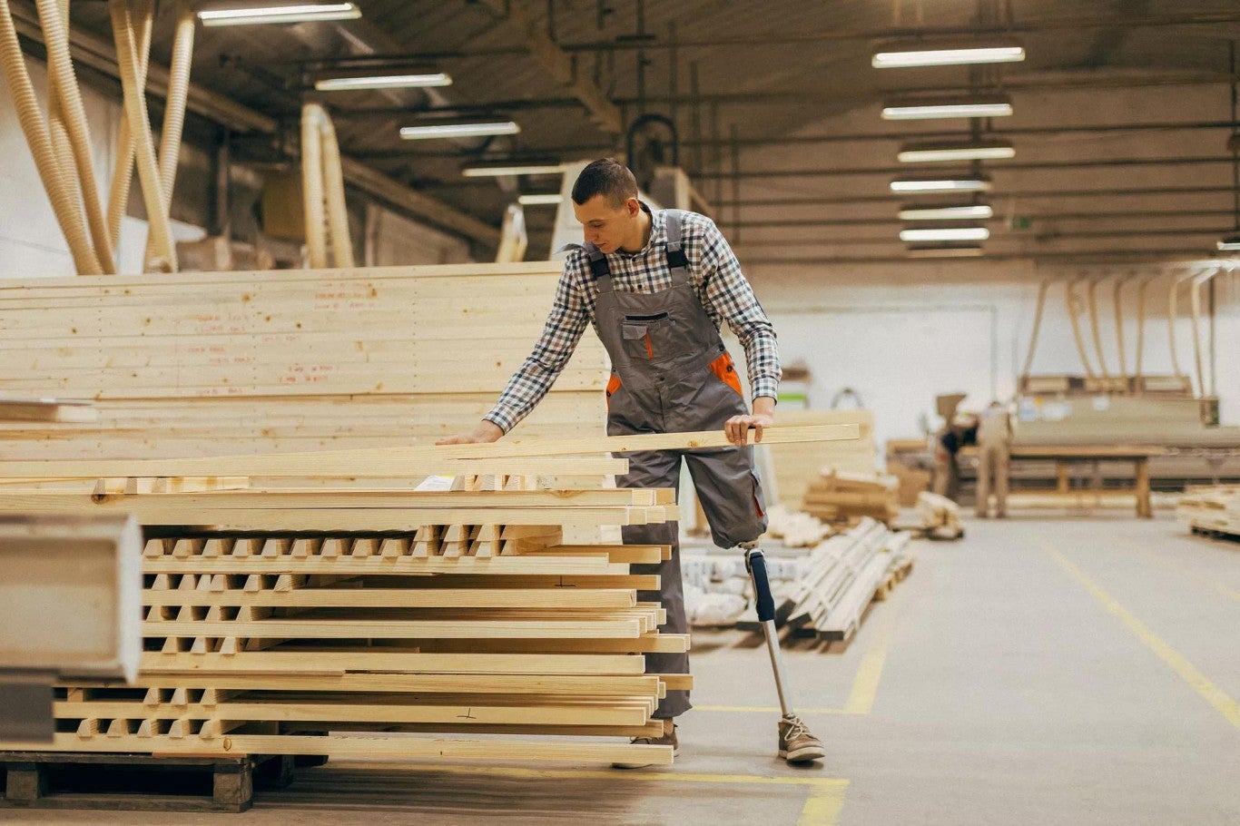 Man with prosthetic leg selecting lumber for manufacturing