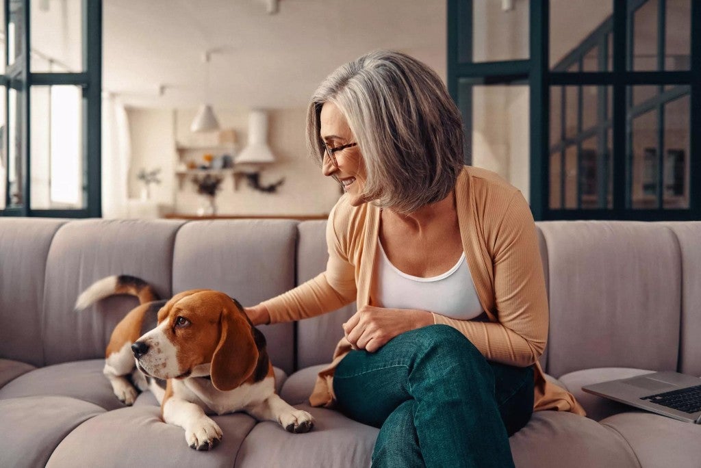 A woman petting her dog in her home.