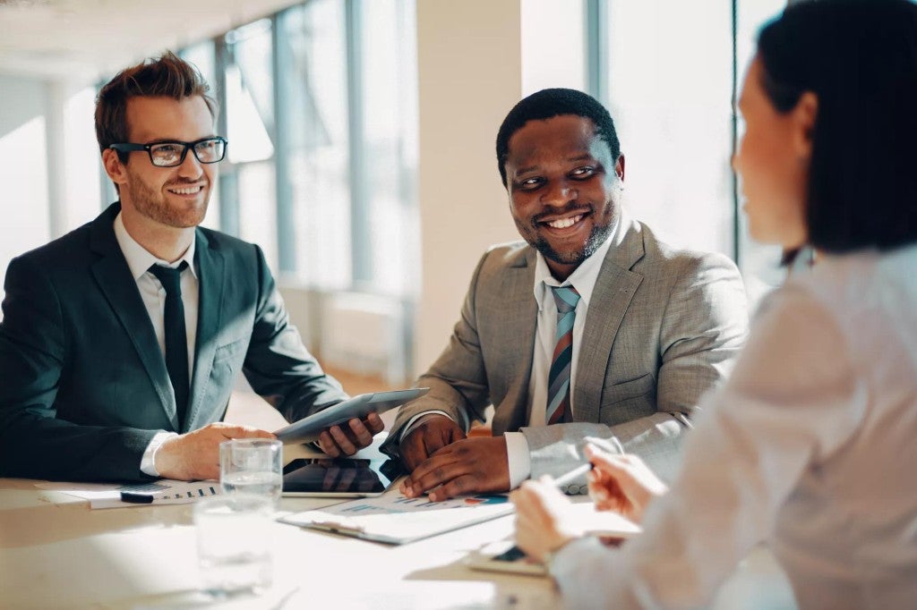 Two men and a woman meeting in an office setting.