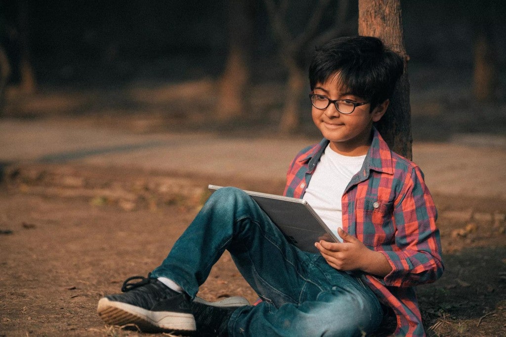 A boy sitting outside with a sketchpad.