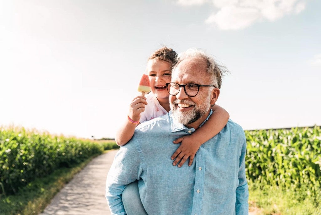 A happy man and his grandchild outdoors.