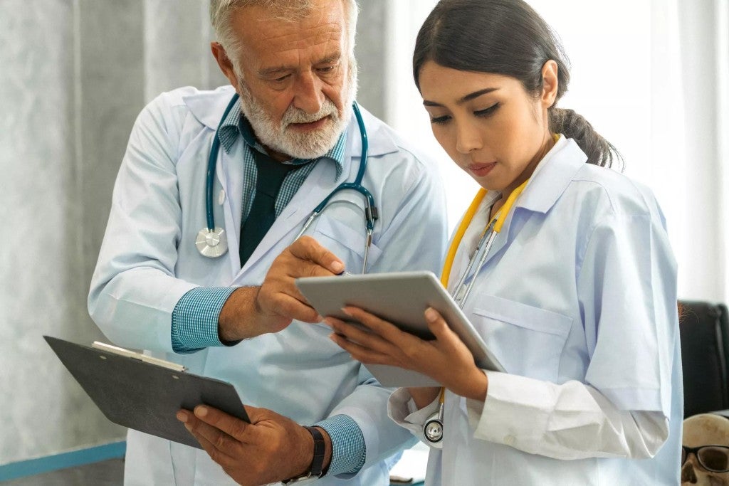 Experienced doctor looking at a notepad with a younger doctor.