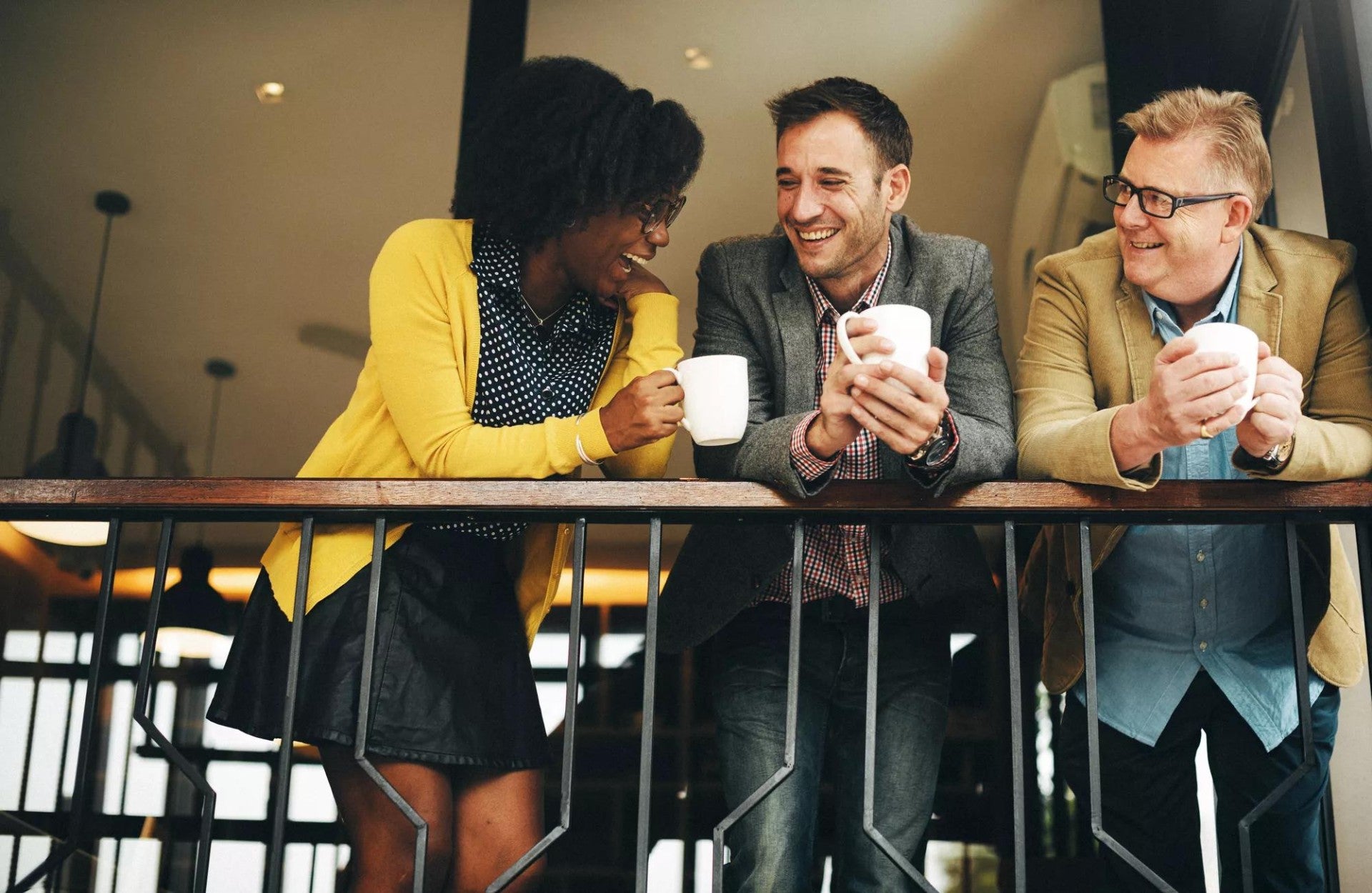 A group of three employees chatting on a balcony.