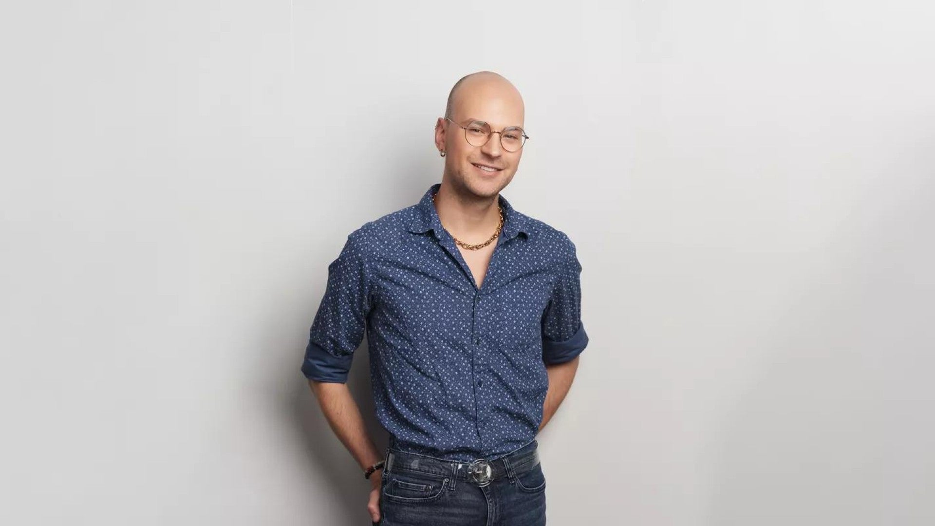 Tanner Mote smiling, standing against a white wall